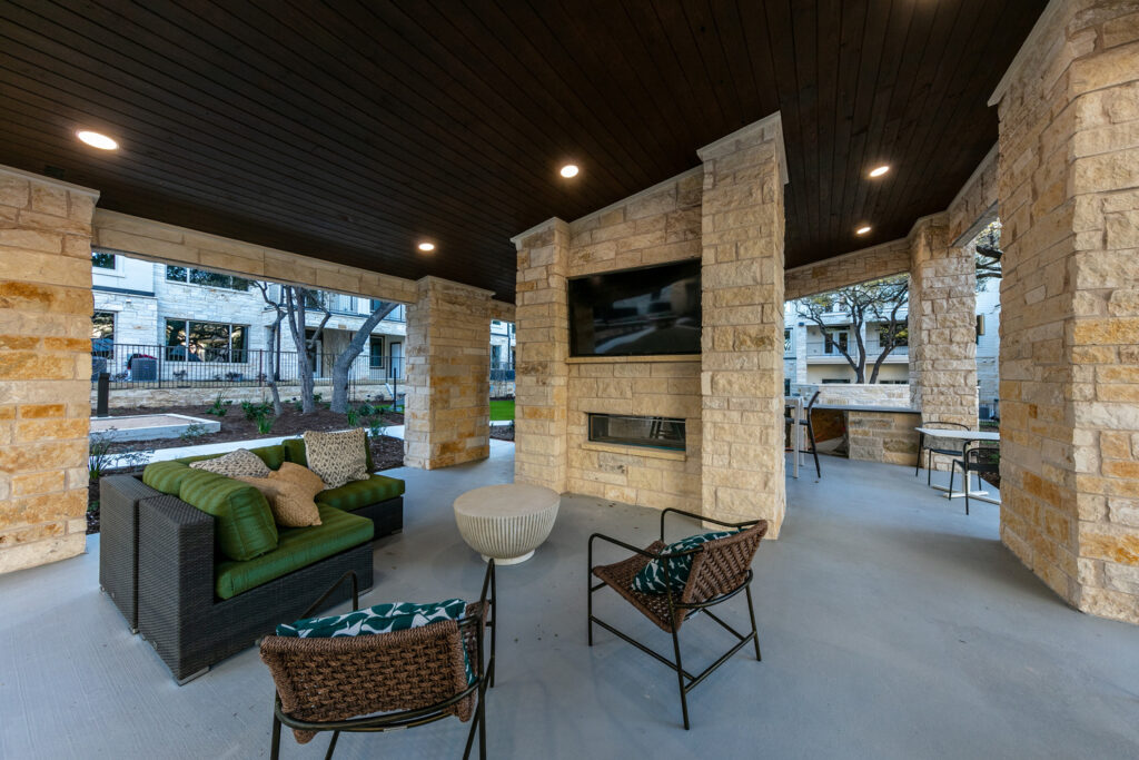 Covered lounge seating with sofa and armchairs facing TV and fireplace