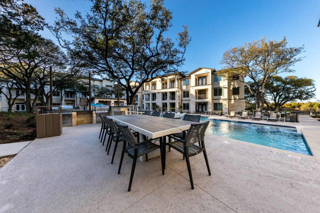 Alternate view of dining table and outdoor kitchen next to resort-style pool
