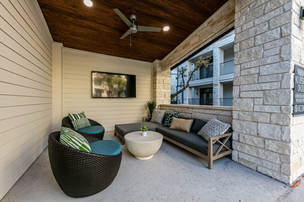 Covered private lounge area with ceiling fan and comfortable seating