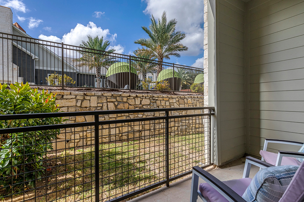 Model apartment patio with lounge seating and view of pool courtyard