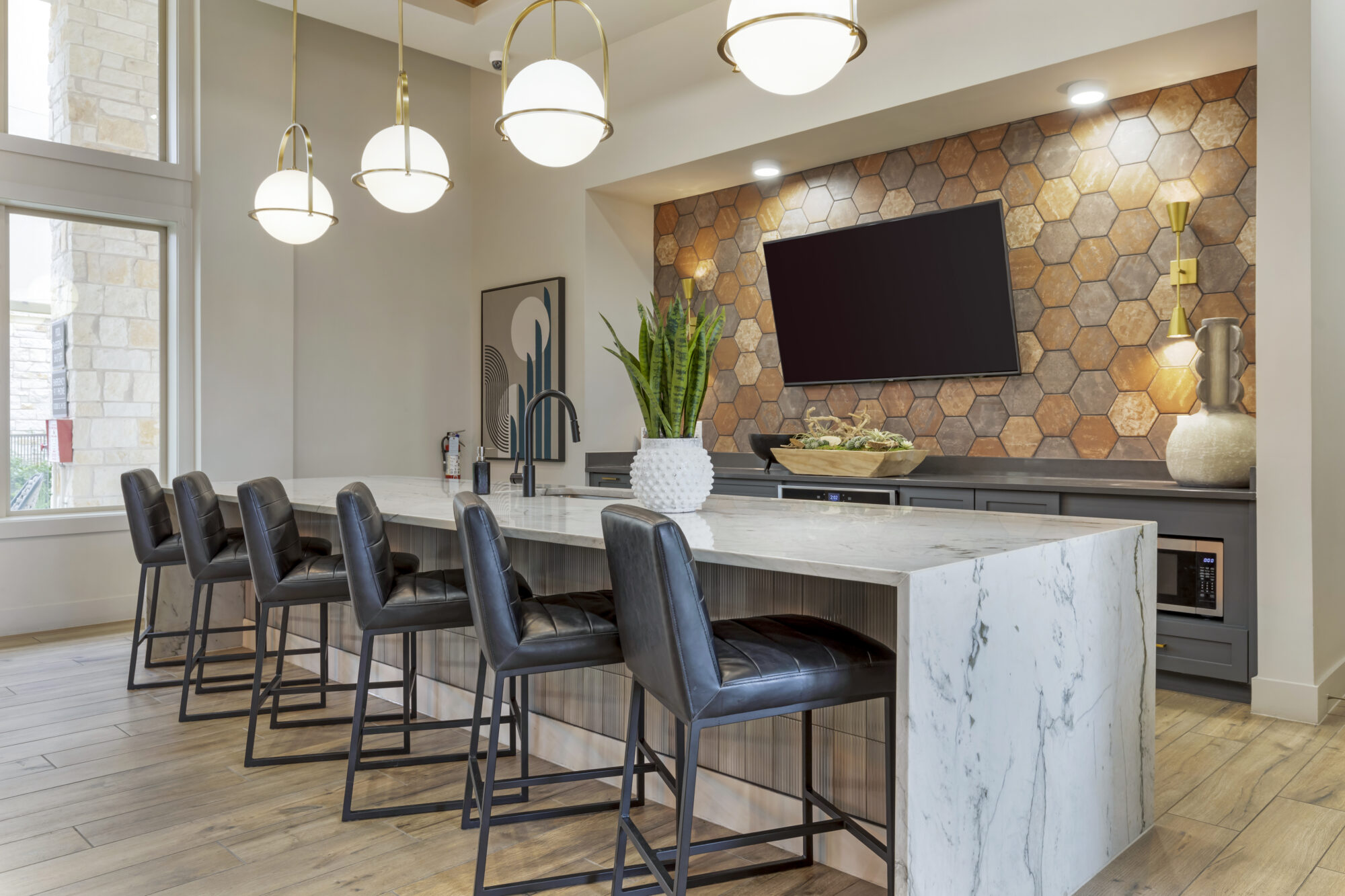 Demonstration kitchen in clubhouse with pendant lighting, barstool seating, and wall-mounted TV